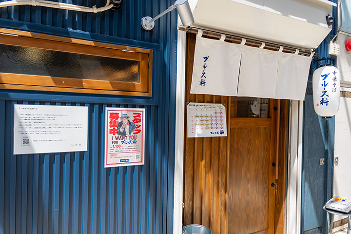 「福岡・西新のラーメン店ブルース軒」外観 深いブルーの壁と白いのれんが目印